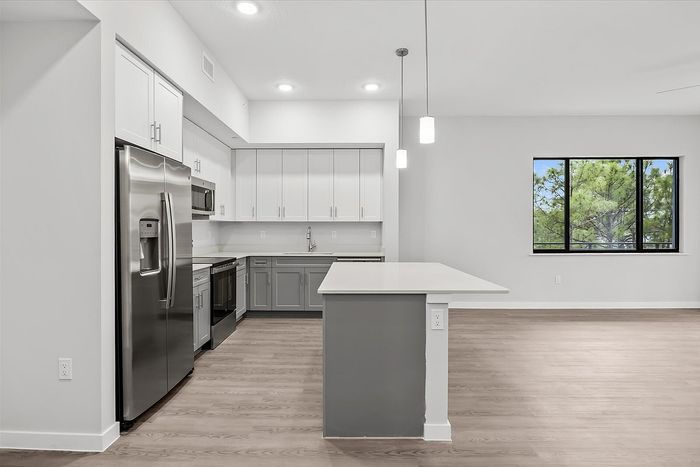 Modern kitchen with sleek stainless steel appliances, stylish cabinetry, and elegant pendant lighting, complementing a spacious island ideal for cooking and entertaining.