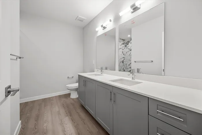 Elegant bathroom featuring a modern double sink vanity with sleek gray cabinetry and large mirrors.