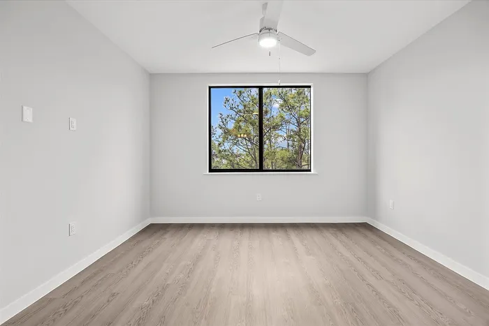Bright and airy room with large window showcasing a stunning view of lush greenery, perfect for relaxation.