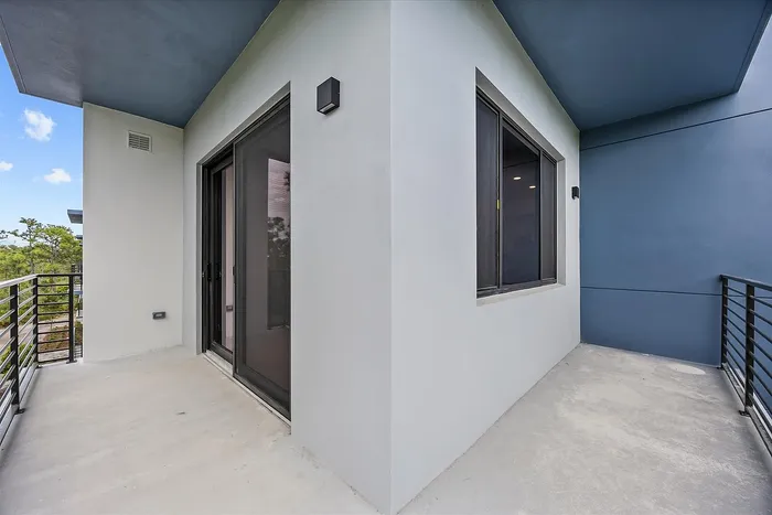Modern balcony with sleek railing and large sliding doors, offering a serene view perfect for relaxation.
