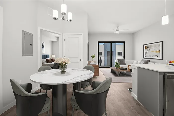 Contemporary open-concept living area with elegant dining space, cozy seating, and abundant natural light from large windows.