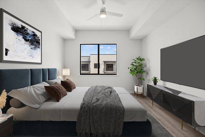 Elegant bedroom with a modern design, featuring a plush bed, stylish artwork, natural light from the window, and sleek furniture accents.