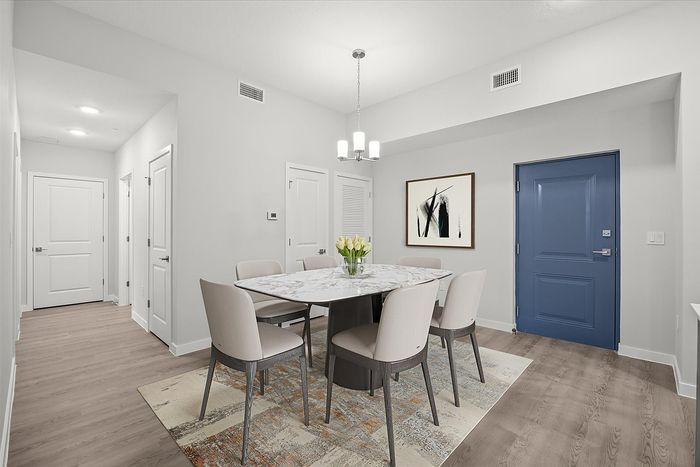 Sophisticated dining area with a chic marble table, stylish chairs, modern art, and a vibrant blue door, perfect for elegant gatherings.