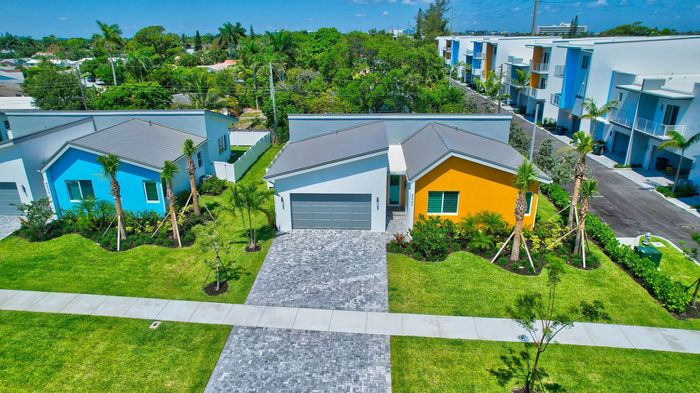 Aerial view of modern single-family homes with colorful exteriors, lush landscaped gardens, and a serene suburban ambiance.