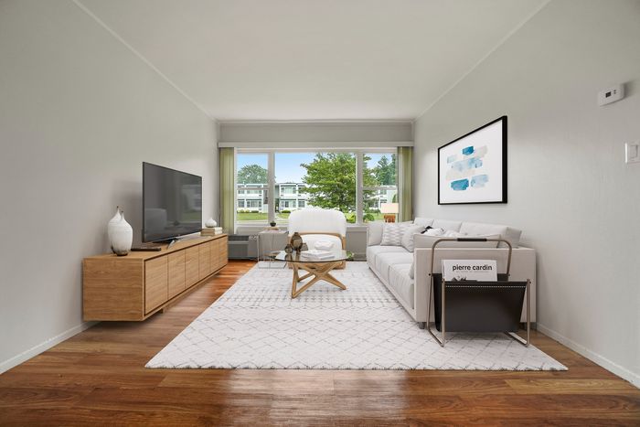 Bright and inviting living room with elegant decor, featuring a large window with scenic views, plush sofa, and modern entertainment center.