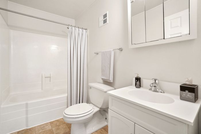 Bright and modern bathroom with pristine white fixtures, sleek vanity, and elegant ceramic tile flooring.