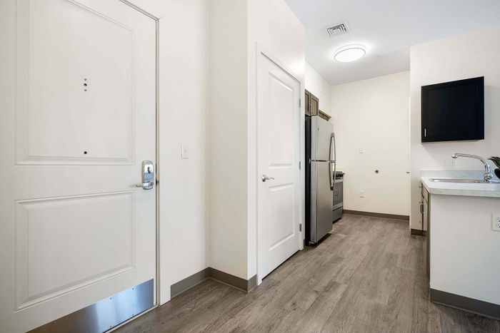 Modern apartment entryway featuring sleek hardwood floors, stainless steel appliances, and elegant lighting.