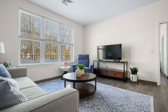 Bright and inviting living room with a comfy couch, elegant armchair, and large window offering scenic views, perfect for relaxation.