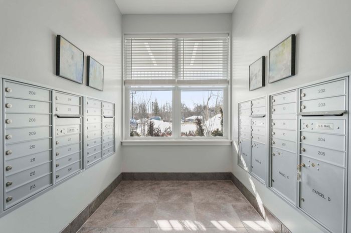 Modern mailroom with sleek mailboxes and large windows offering natural light and a view of a snowy landscape.