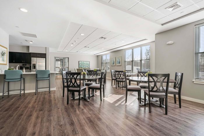 Modern apartment community space featuring elegant hardwood floors, a stylish kitchen with stainless steel appliances, and a bright seating area with abundant natural light.