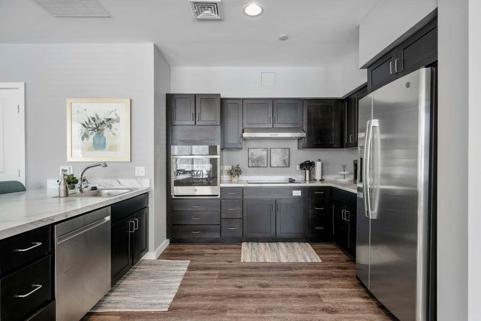 Modern kitchen with sleek dark cabinetry, stainless steel appliances, and elegant marble countertops, perfect for culinary creativity.
