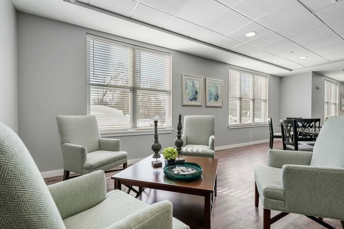 Elegant and cozy living room with soft armchairs, a stylish coffee table, and large sunlit windows, perfect for relaxation and socializing.