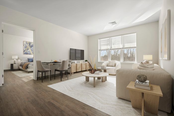 Bright and modern living room with elegant decor, open dining area, cozy bedroom view, and large sunlit windows.