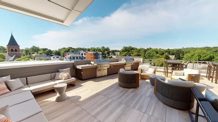 Luxurious outdoor terrace with modern seating, gourmet grills, and panoramic views of lush greenery and charming architecture.