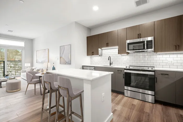 Modern open-plan living area with sleek kitchen, stylish breakfast bar, and cozy lounge. Bright, inviting space with elegant wooden flooring and contemporary decor.