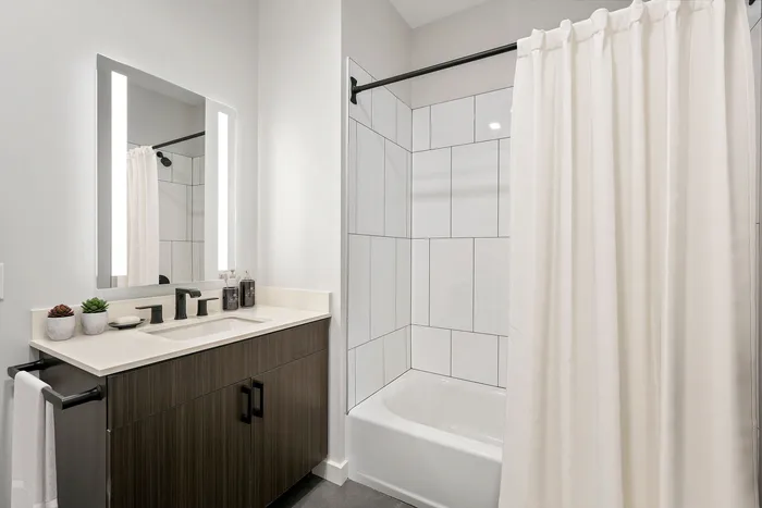 Modern bathroom featuring sleek vanity with dual sinks, elegant wooden cabinetry, and bright lighting.