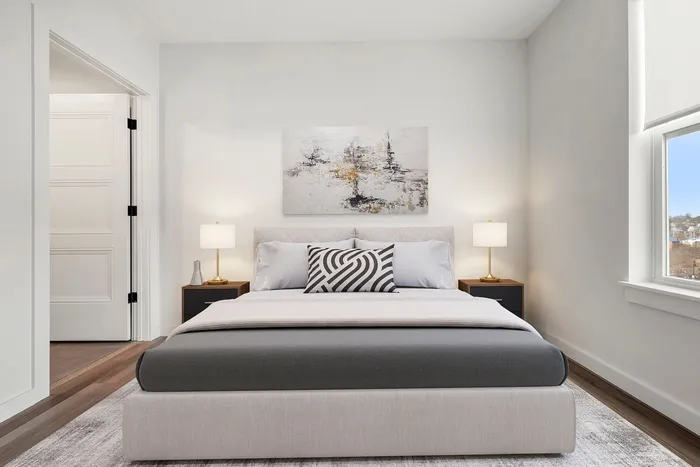 Elegant bedroom with modern decor, featuring a plush bed, chic artwork, and ample natural light.