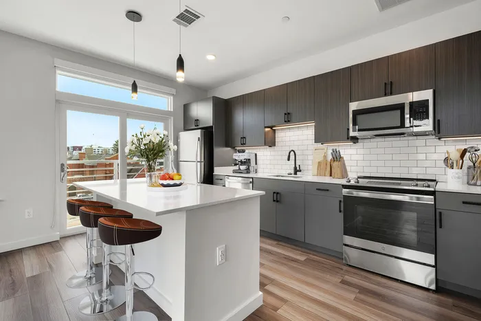 Modern kitchen with sleek gray cabinets, white subway tile backsplash, and a spacious island with elegant pendant lighting.