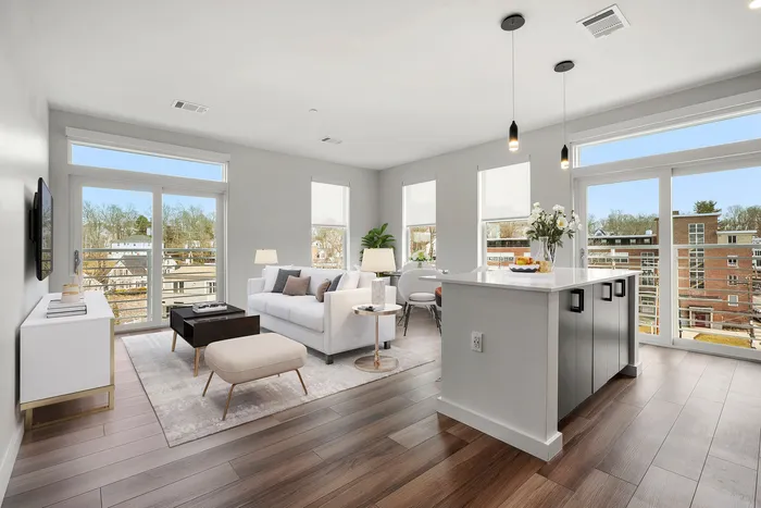 Bright, modern living area with hardwood floors, elegant decor, and large windows offering scenic outdoor views.