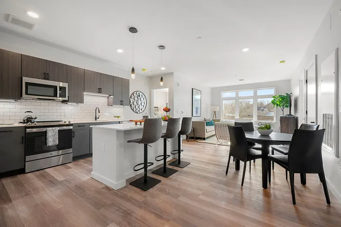 Modern open-concept kitchen and living area with sleek cabinetry, breakfast bar, and vibrant natural lighting.