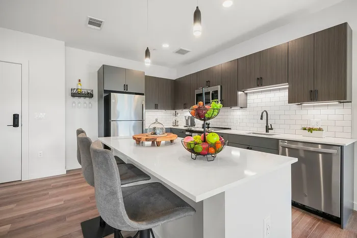 Modern kitchen with sleek cabinetry, stainless steel appliances, and a stylish island featuring elegant bar seating, perfect for entertaining.