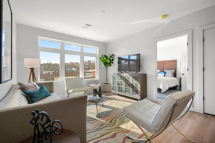Bright, inviting living room featuring modern decor, natural light, and a view into a cozy bedroom.