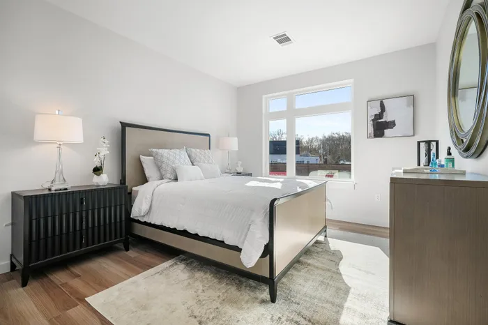 Bright and airy bedroom with modern decor, featuring a luxurious bed, elegant nightstands, and a large window providing natural light.