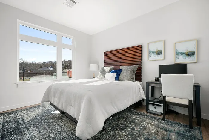 Bright and inviting bedroom with elegant decor, featuring a plush bed, stylish headboard, and a serene view through large windows.