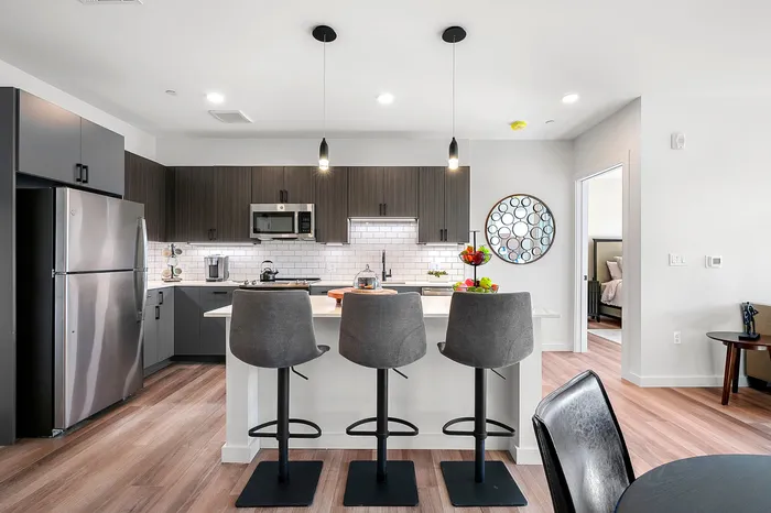 Modern kitchen with sleek cabinetry, stainless steel appliances, and a stylish island with high-back chairs, perfect for entertaining.