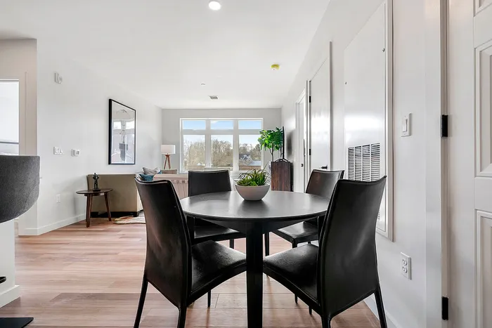 Bright and modern open-plan dining and living area with large windows offering scenic views, featuring elegant furniture and stylish decor.