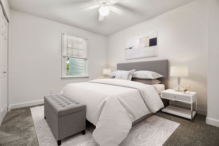 Inviting bedroom with elegant décor, plush carpet, and natural light filtering through a window, offering a serene and cozy atmosphere.