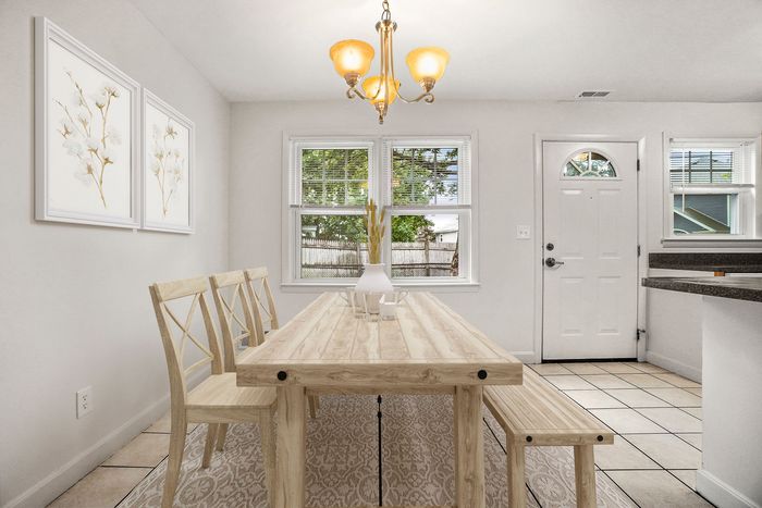 Bright dining area with elegant wooden table and chairs, soft lighting, and charming wall art, offering a warm and inviting atmosphere.