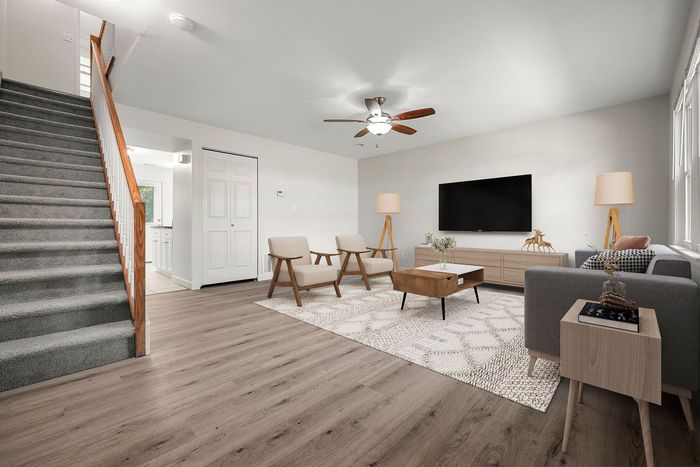 Bright and inviting living room with modern wooden flooring, cozy seating area, stylish decor, and natural light pouring in.