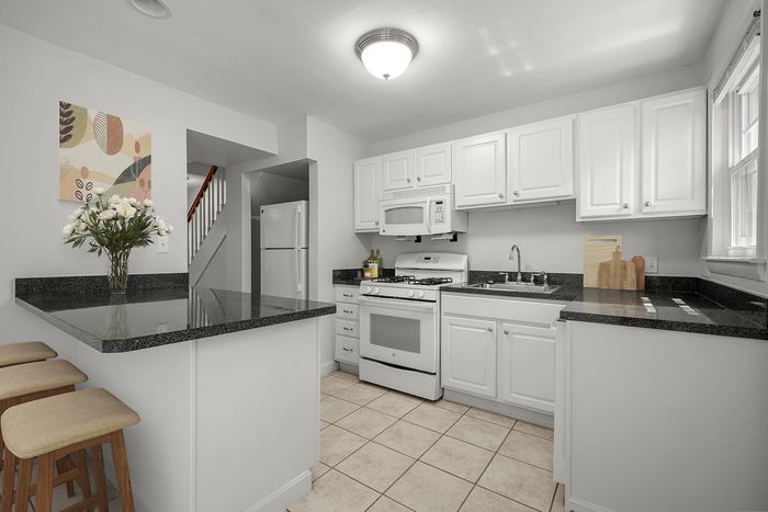 Bright and inviting kitchen with sleek black countertops, modern appliances, and cozy breakfast bar.