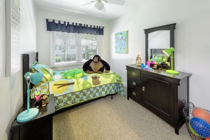 Bright and inviting child's bedroom with colorful bedding, plush toys, and stylish dark wood furniture, perfect for a playful atmosphere.