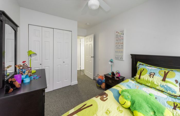 Charming children's bedroom with vibrant decor, featuring a playful animal-themed bedspread, cozy carpet, and ample storage space.