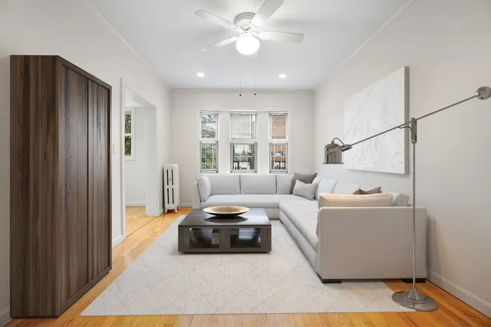Bright and modern living room with a sleek L-shaped sofa, chic floor lamp, and elegant coffee table. Natural light streams through large windows, accentuating the cozy ambiance.