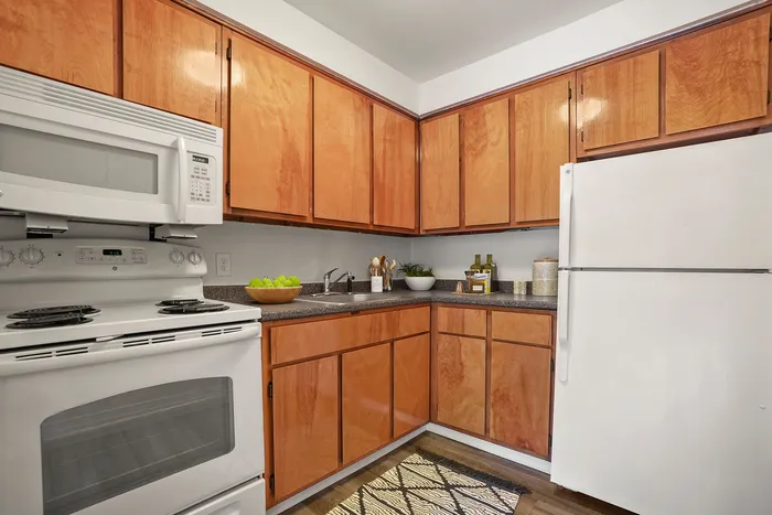 Charming and efficient kitchen with warm wood cabinets, modern appliances, and cozy countertop accessories.