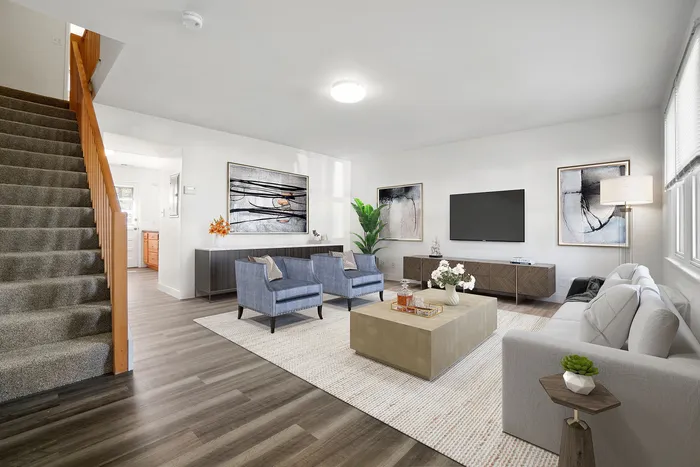Elegant living room showcasing contemporary furniture, a soft grey couch, and stylish blue armchairs, complemented by modern art and warm lighting.
