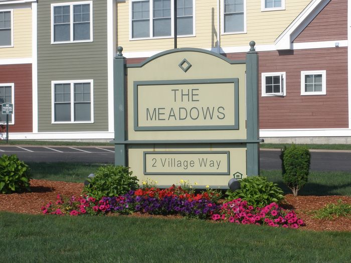Charming apartment complex at The Meadows with vibrant garden and modern architecture on 2 Village Way.