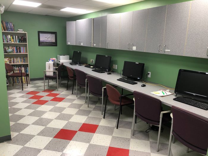 Inviting study room with multiple computers, vibrant bookshelves, and a stylish red-accented floor, perfect for focused work and learning.