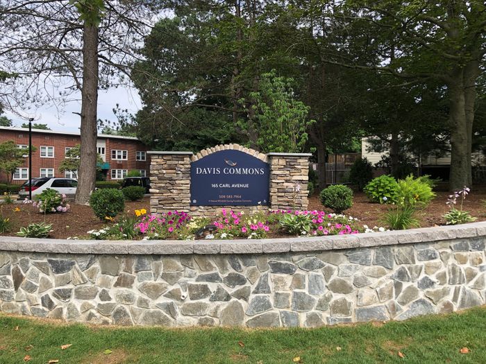 Charming entrance to Davis Commons with vibrant landscaping and elegant stonework at 165 Carl Avenue.