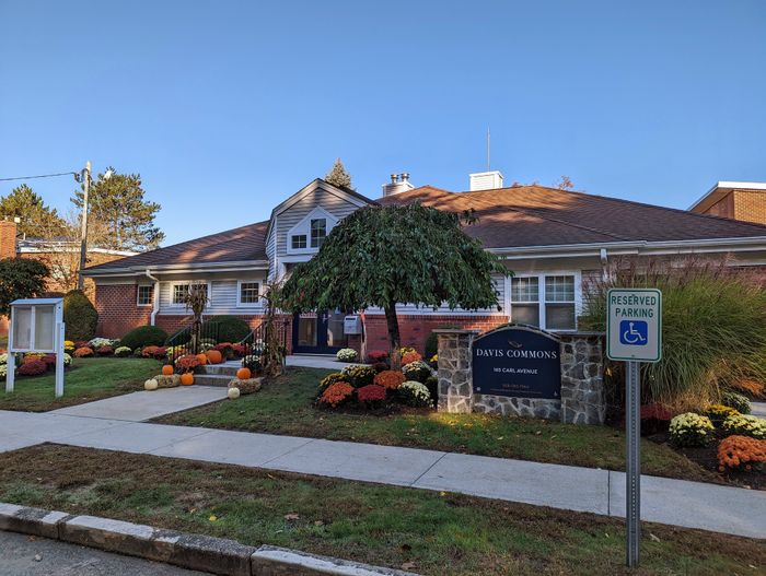 Charming residential building with welcoming entrance, surrounded by vibrant autumn landscaping and reserved parking.