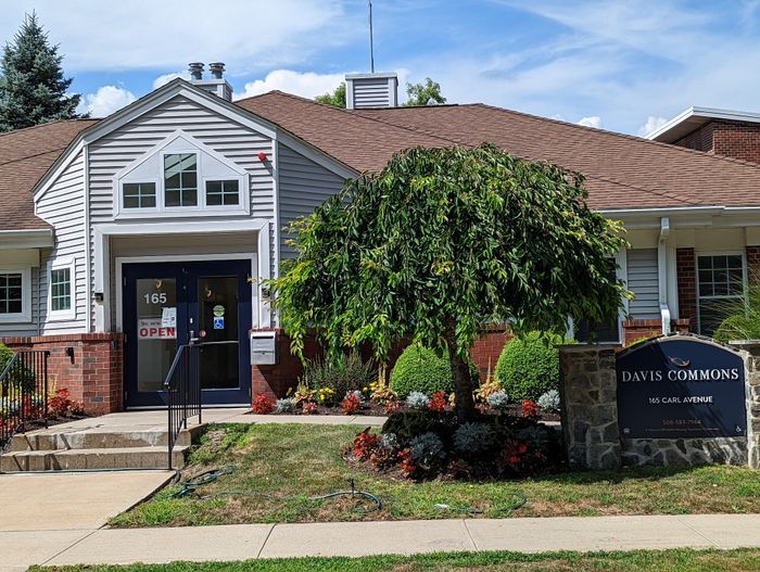 Inviting entrance of Davis Commons with charming landscaping and welcoming signs at 165 Carl Avenue.