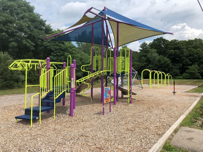 Vibrant playground featuring colorful climbing structures and slides, nestled in a lush green park, perfect for family fun and outdoor activities.