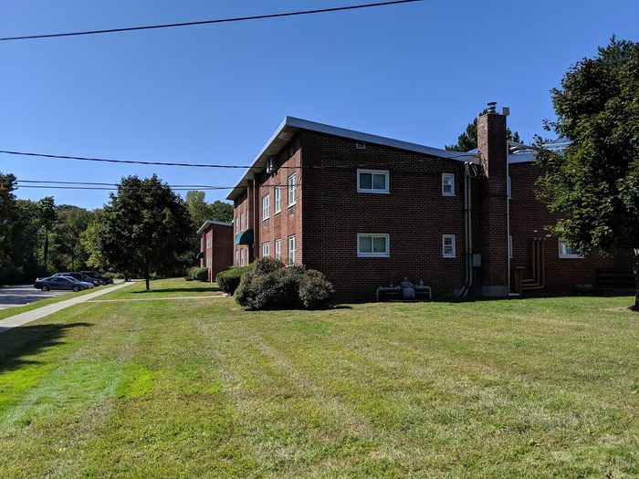 Charming brick apartment building in a serene setting with lush green lawns, perfect for enjoying peaceful living in a well-maintained community.