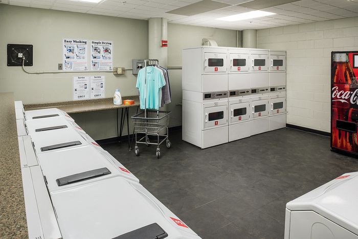Modern apartment laundry room with multiple washers and dryers, sleek countertops, and a convenient vending machine.