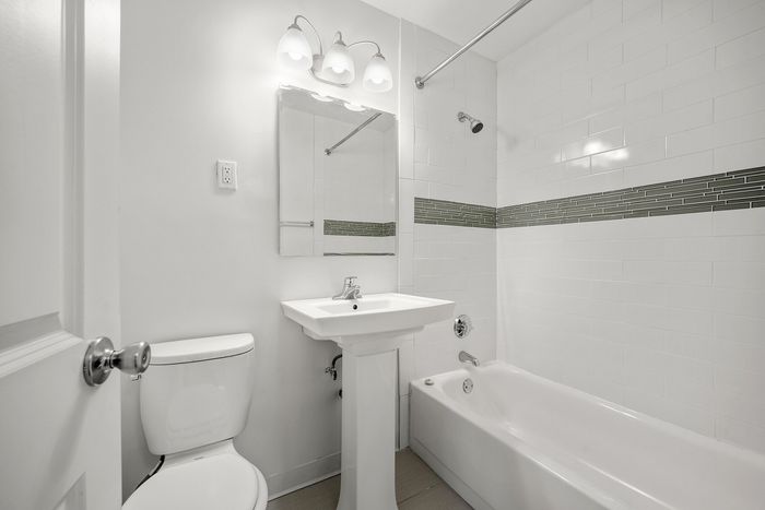 Elegant bathroom with modern fixtures, a sleek pedestal sink, and clean white tile design.