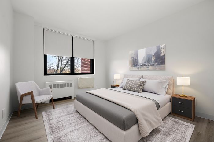 Bright and modern bedroom with elegant d&eacute;cor, featuring a cozy bed, stylish armchair, and large window with a serene view.