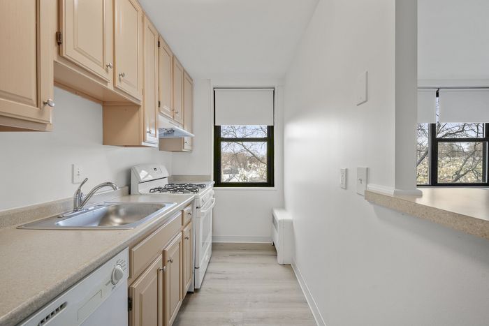 Bright, modern kitchen featuring sleek cabinetry, spacious countertops, and large window with serene views.